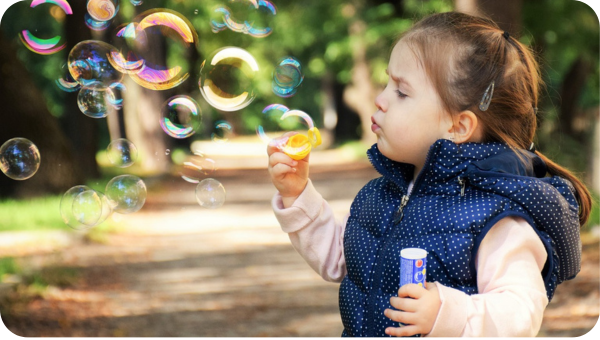 A young girl is blowing bubbles